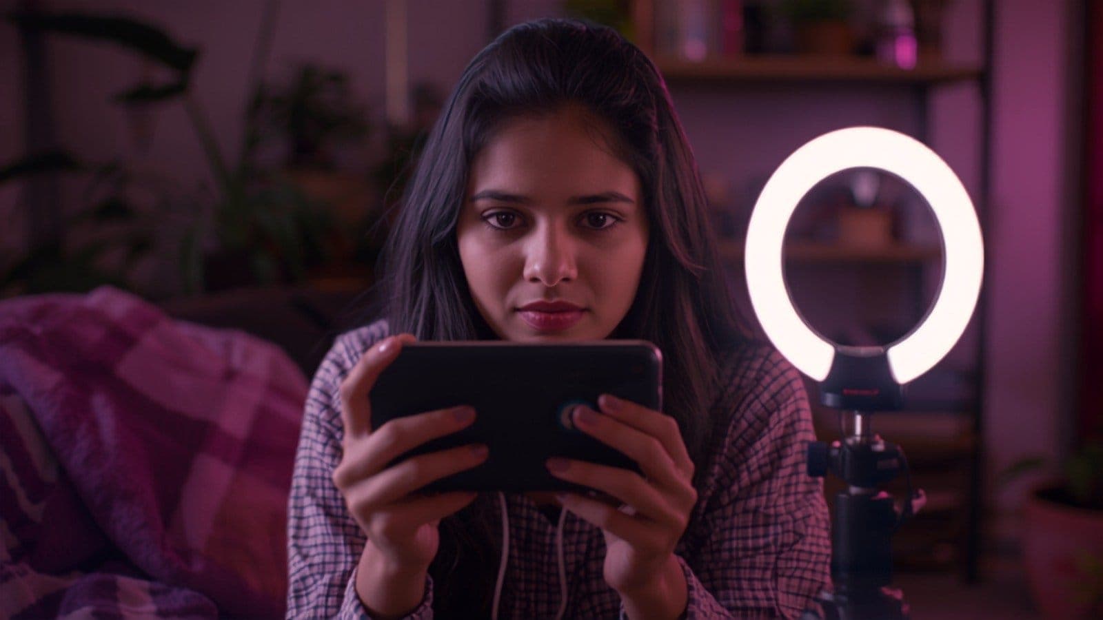 A smartphone on a tripod filming a product on a soft pink studio desk, illustrating the difference between UGC creation and influencer marketing for Indian brands
