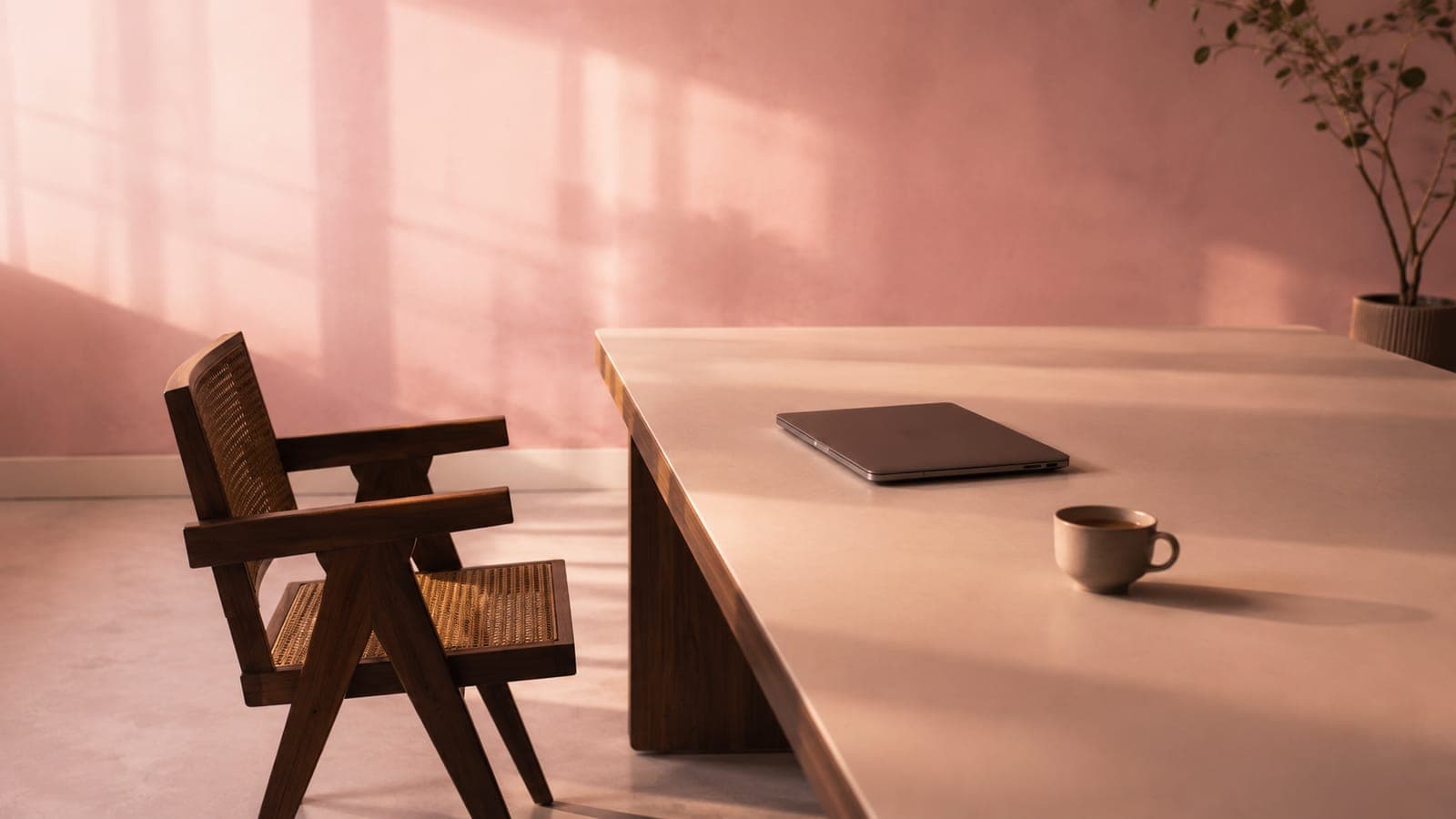 An empty office chair in front of a wide pink-lit desk, suggesting a meeting that didn't happen